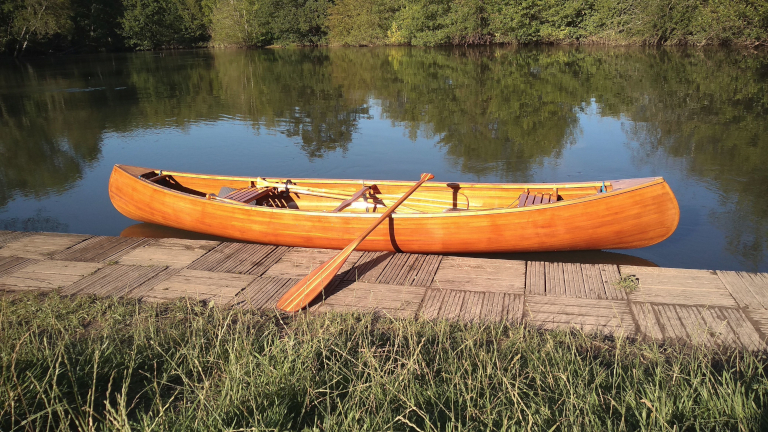 Image 2 - Canoe with a paddle on its gunwale, moored on a wooden pontoon on a river, side view