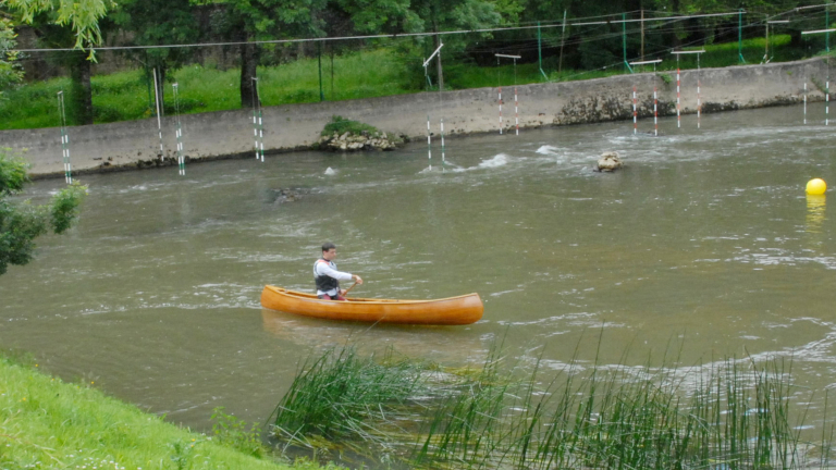 Image 5 - Solo canoe paddler paddling on a river close to a slalom course